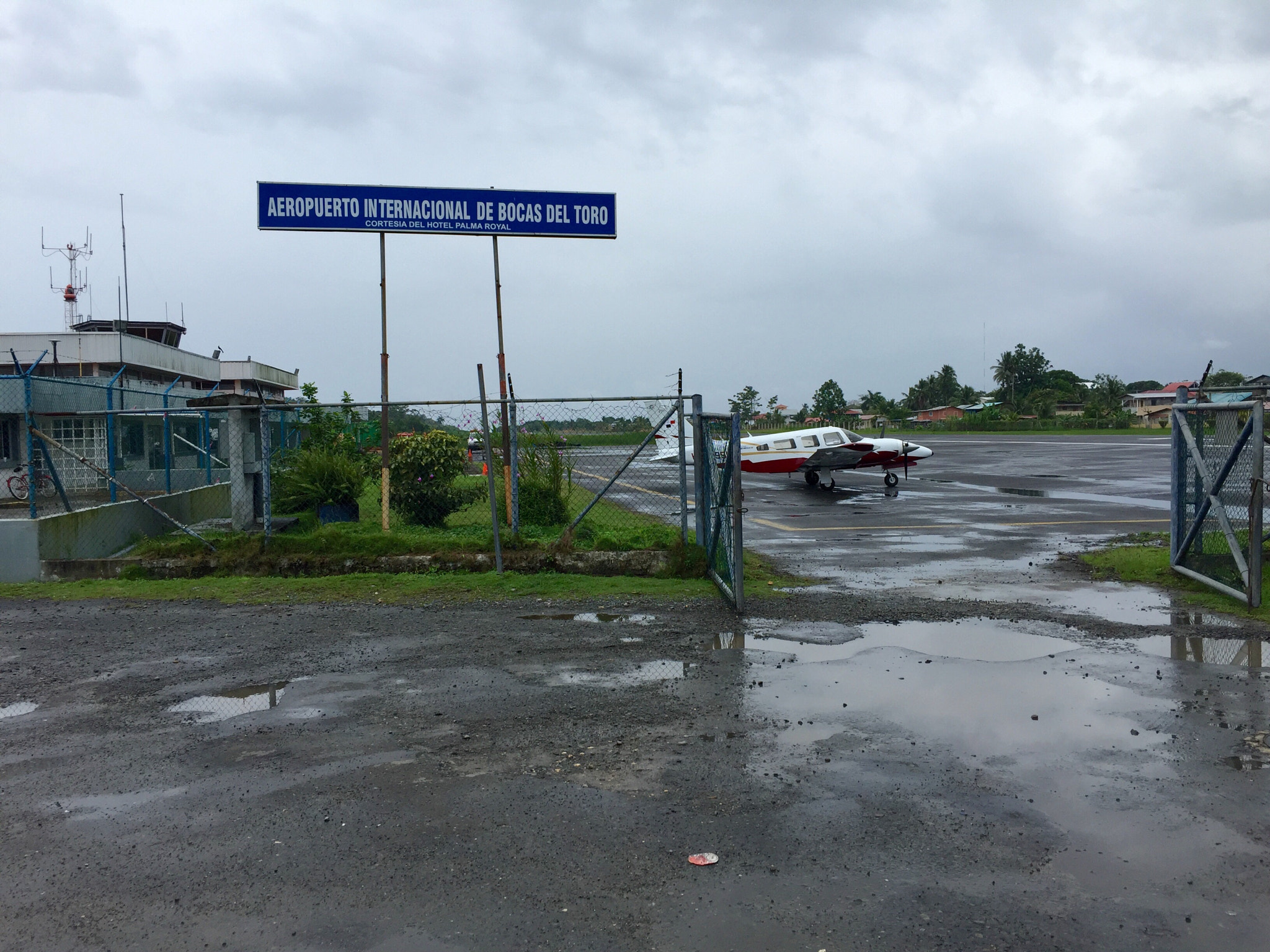 The entrance to Bocas del Toro airport with a small propeller aircraft on a wet apron