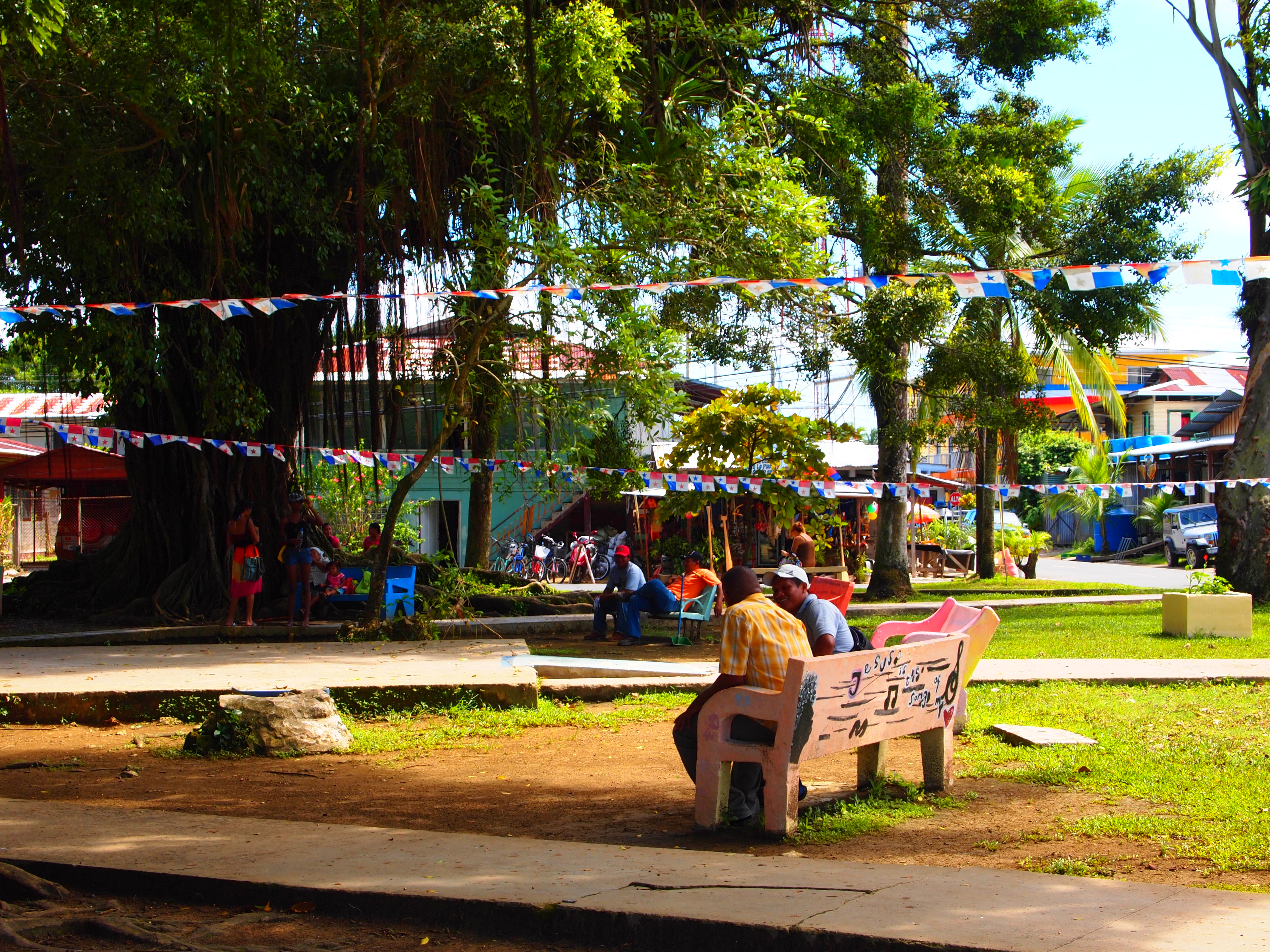 The main plaza in Bocas Town with Panamanian flag bunting and people sitting under trees