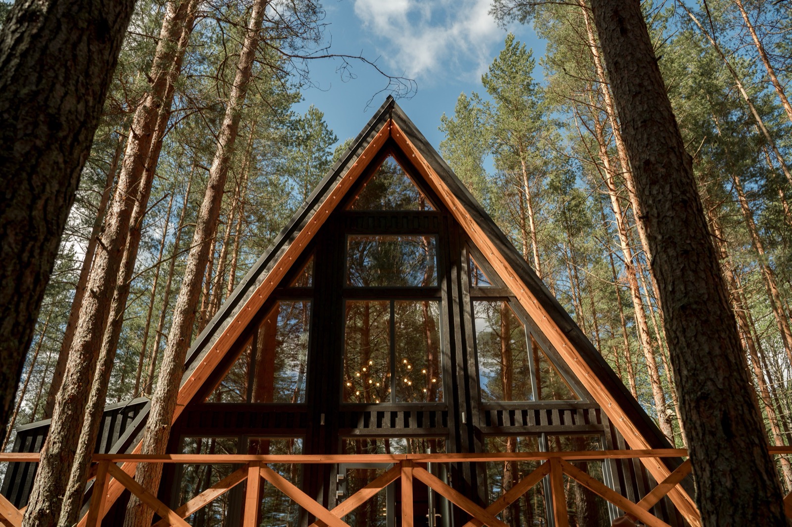 A modern wood and glass A-frame cabin among tall trees