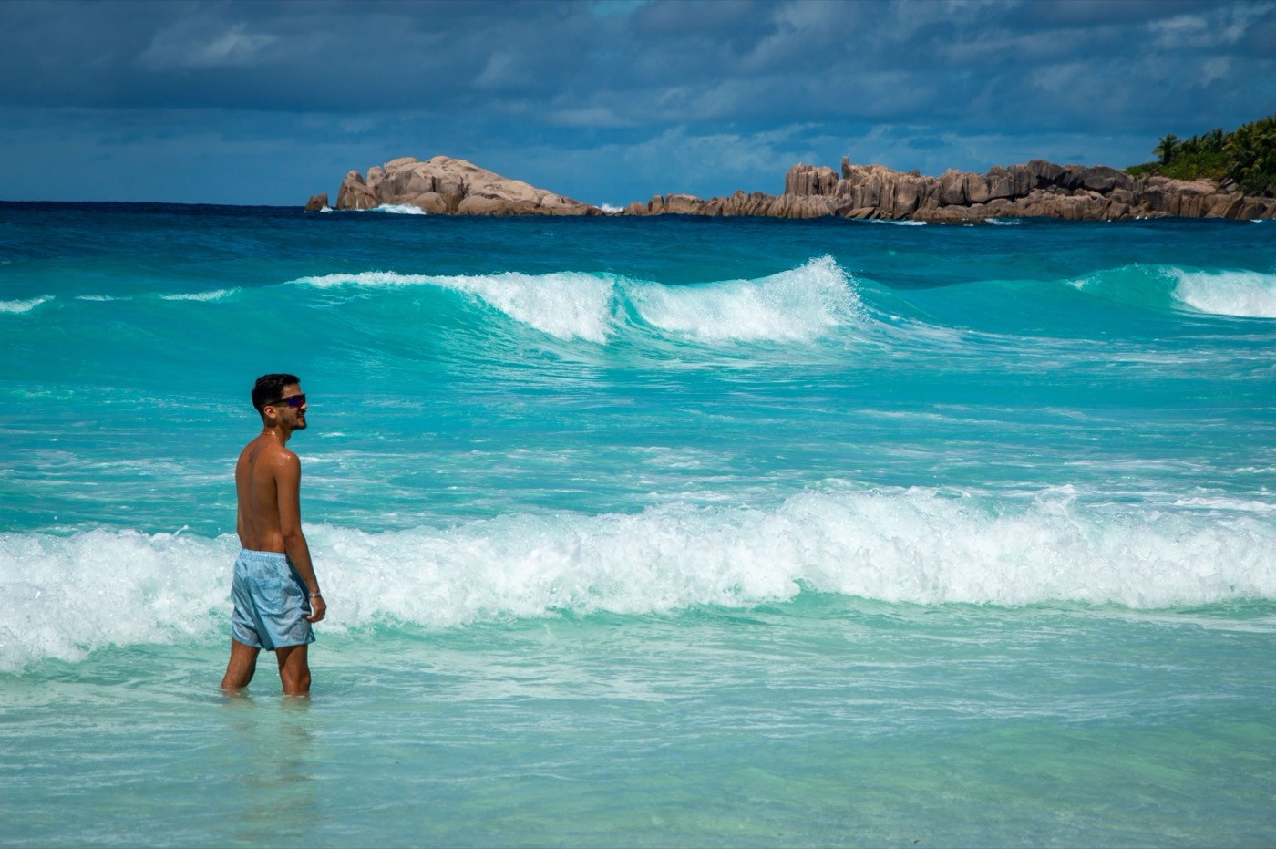 A person standing in turquoise surf on a Grenada beach