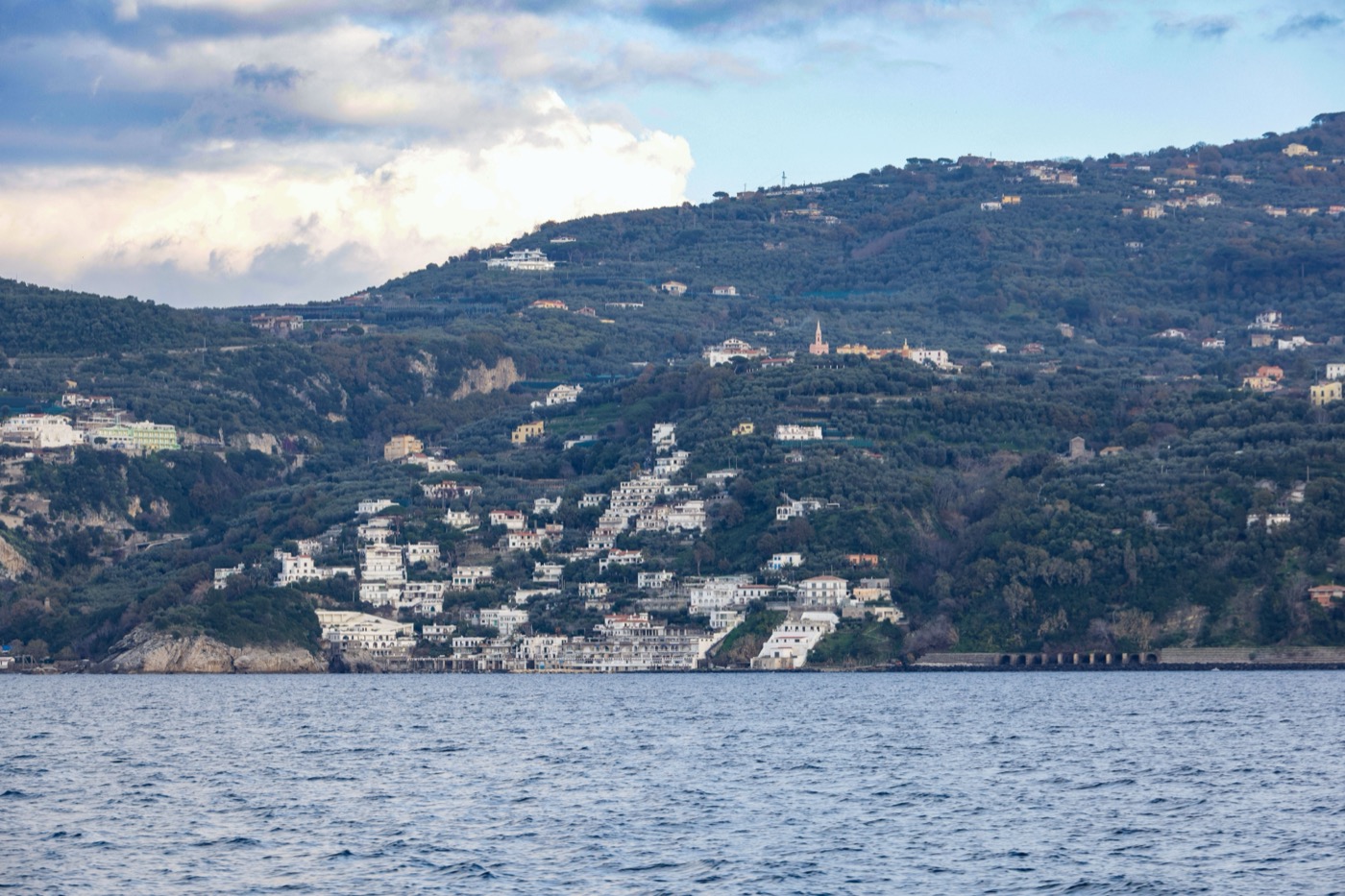 White houses dotting a green hillside above the sea on Jamaica's coast