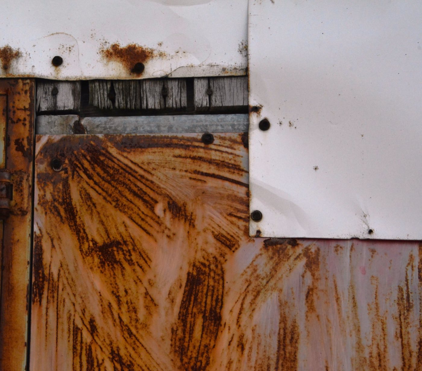Rust streaking down a corrugated steel panel around a metal frame and fixings