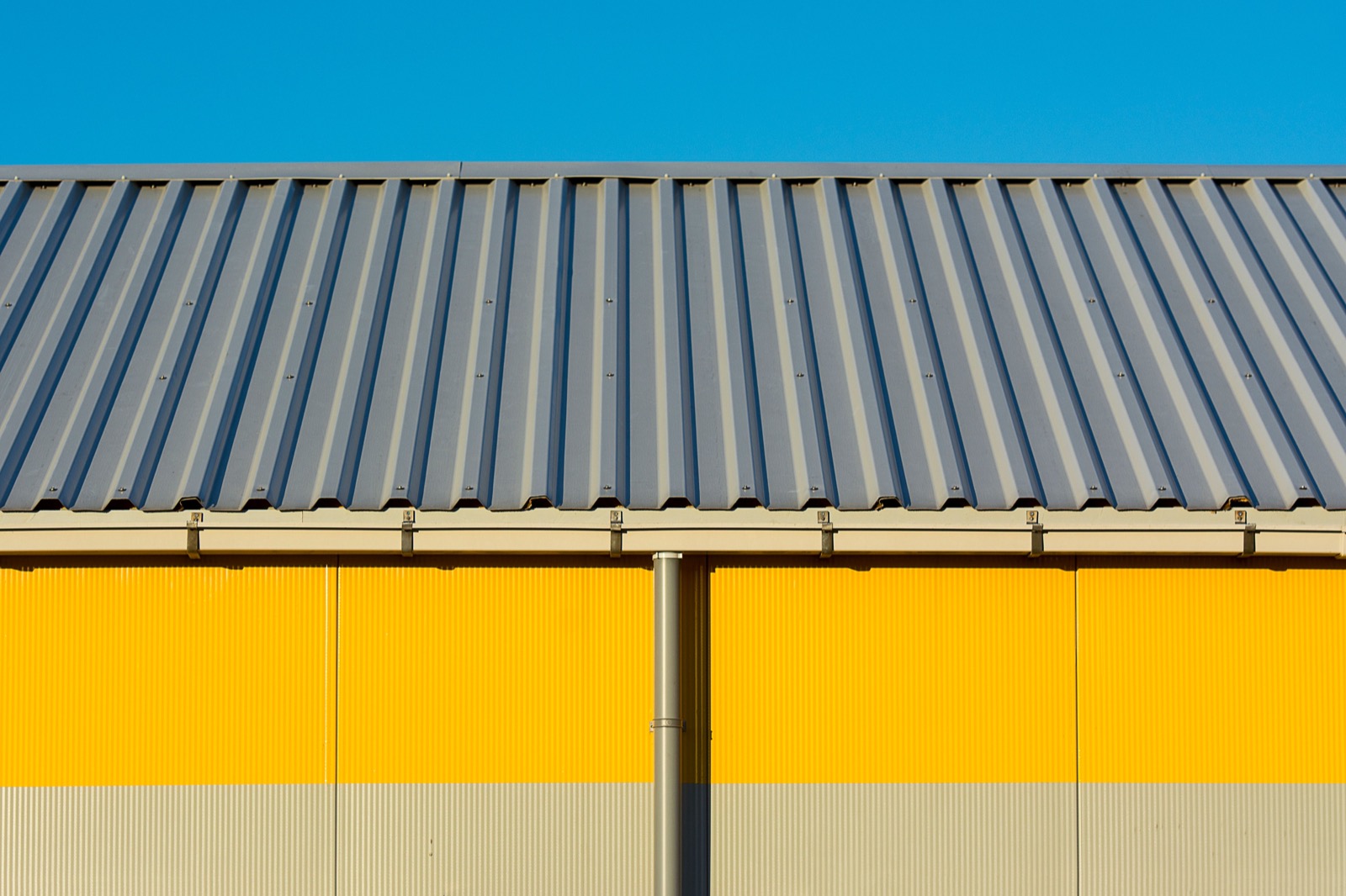A dark corrugated metal roof against a blue sky
